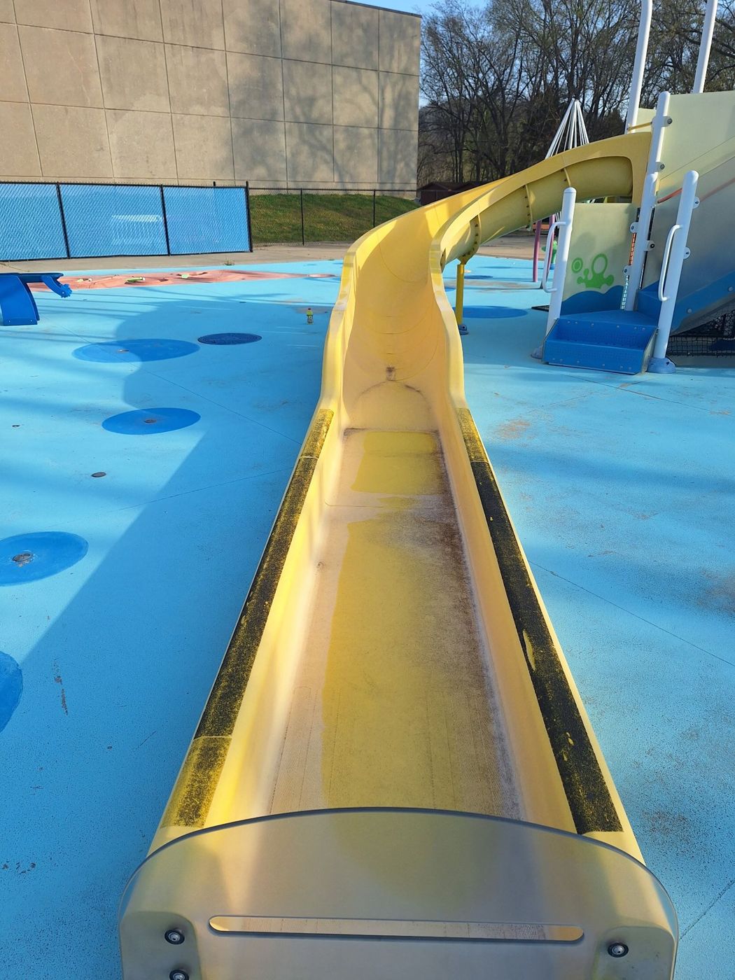 Yellow splash park slide showing worn finish